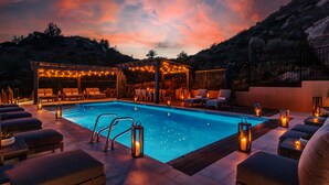 Ein Poolbereich mit Liegestühlen und einer Pergola mit Lichterketten.