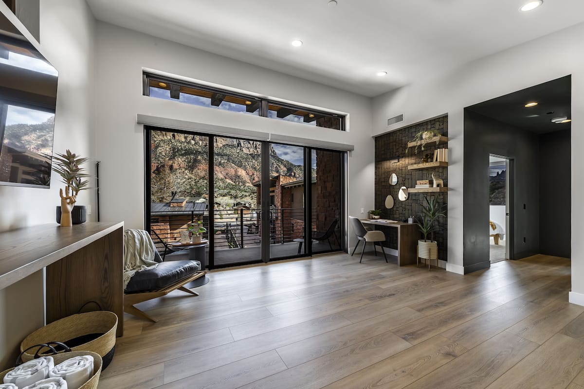 A spacious room with a large sliding glass door leading to an outdoor patio, a built-in desk, and a seating area with a bench.