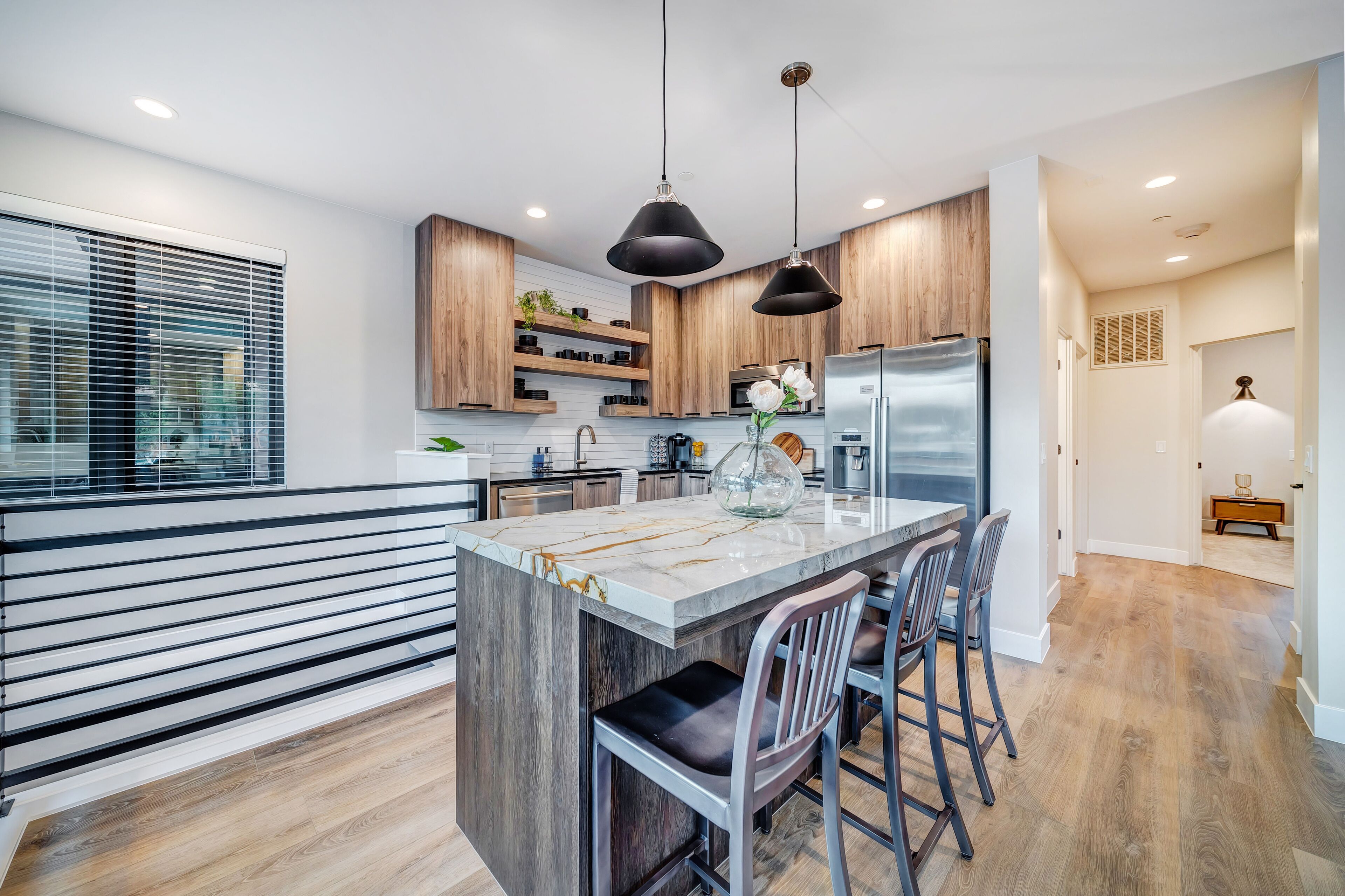 A modern kitchen with a central island, pendant lighting, and wooden cabinetry.