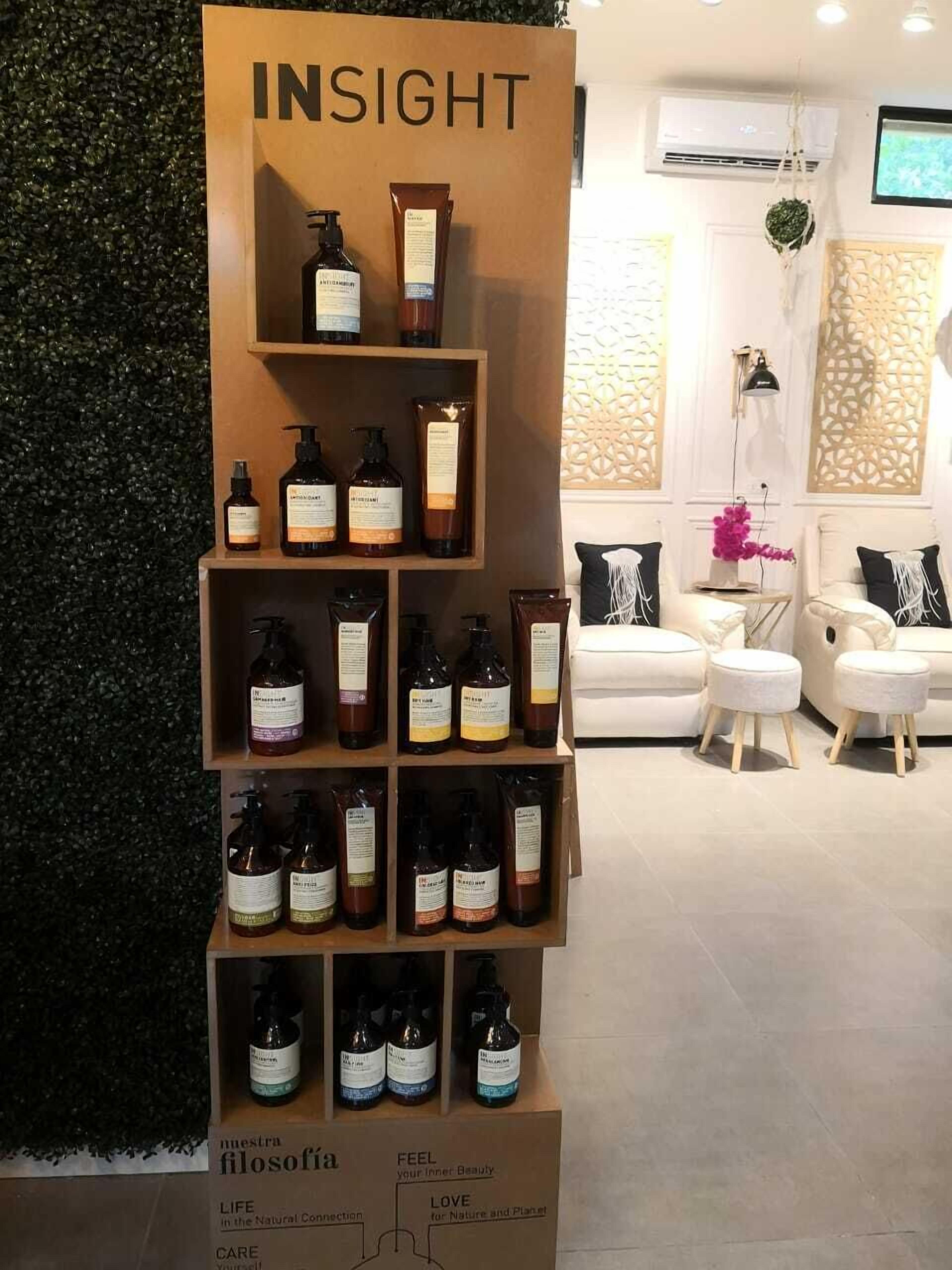 Exposição de produtos Insight numa loja com parede verde e um sofá branco ao fundo.