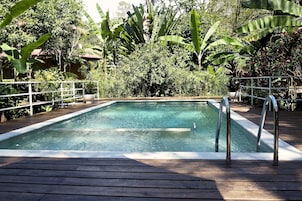 Una piscina al aire libre, sombrillas, sillones reclinables de piscina