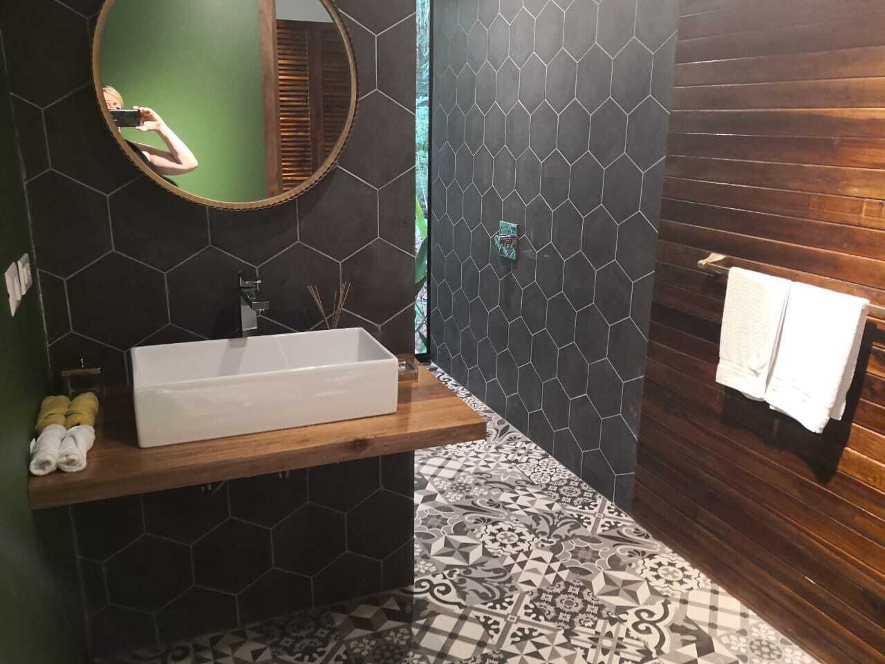 A modern bathroom with a rectangular sink, a round mirror, and a wooden vanity.