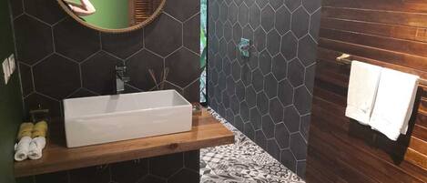 A modern bathroom with a rectangular sink, a round mirror, and a wooden vanity.