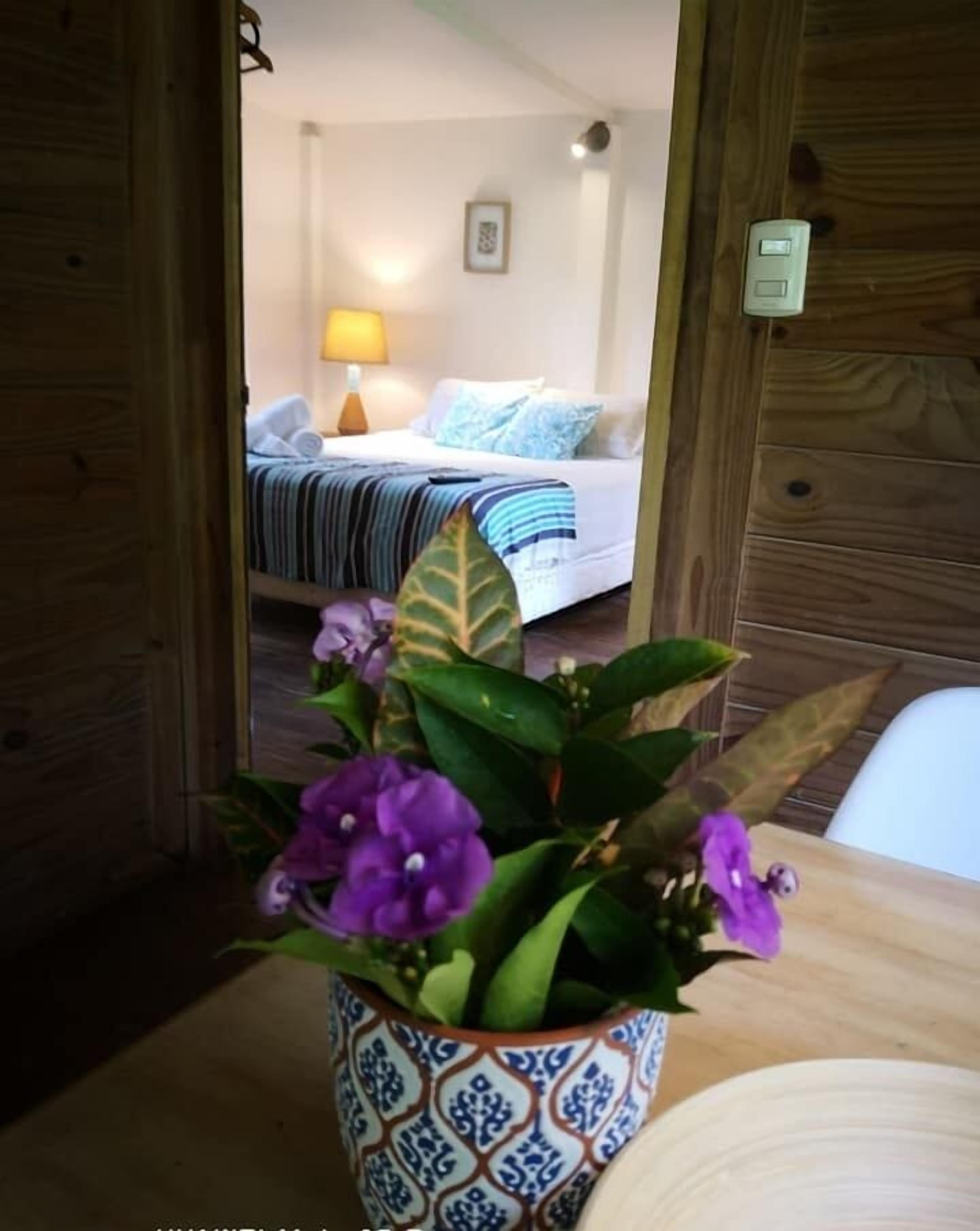 A wooden door leading to a room with a bed, a lamp, and a framed picture on the wall.