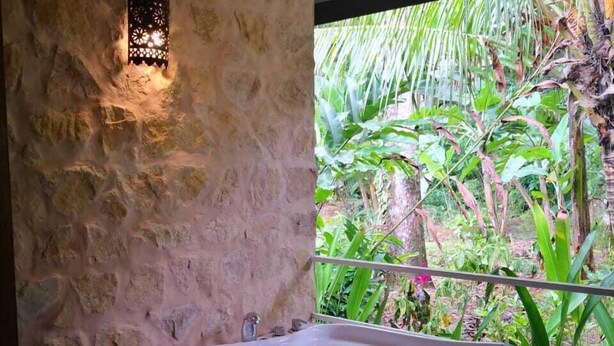 A bathroom with a stone wall, a wooden bathtub, and a hanging light fixture. - Boutique Hotel y Spa Tangara Azul (Ciudad Cortés)