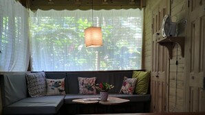 A cozy seating area with a wooden table, a sofa with floral cushions, and a hanging light fixture. - Boutique Hotel y Spa Tangara Azul (Ciudad Cortés)