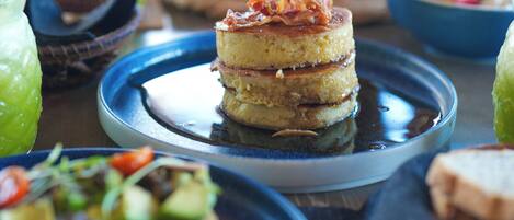 A dining table with various dishes, including pancakes and a salad.