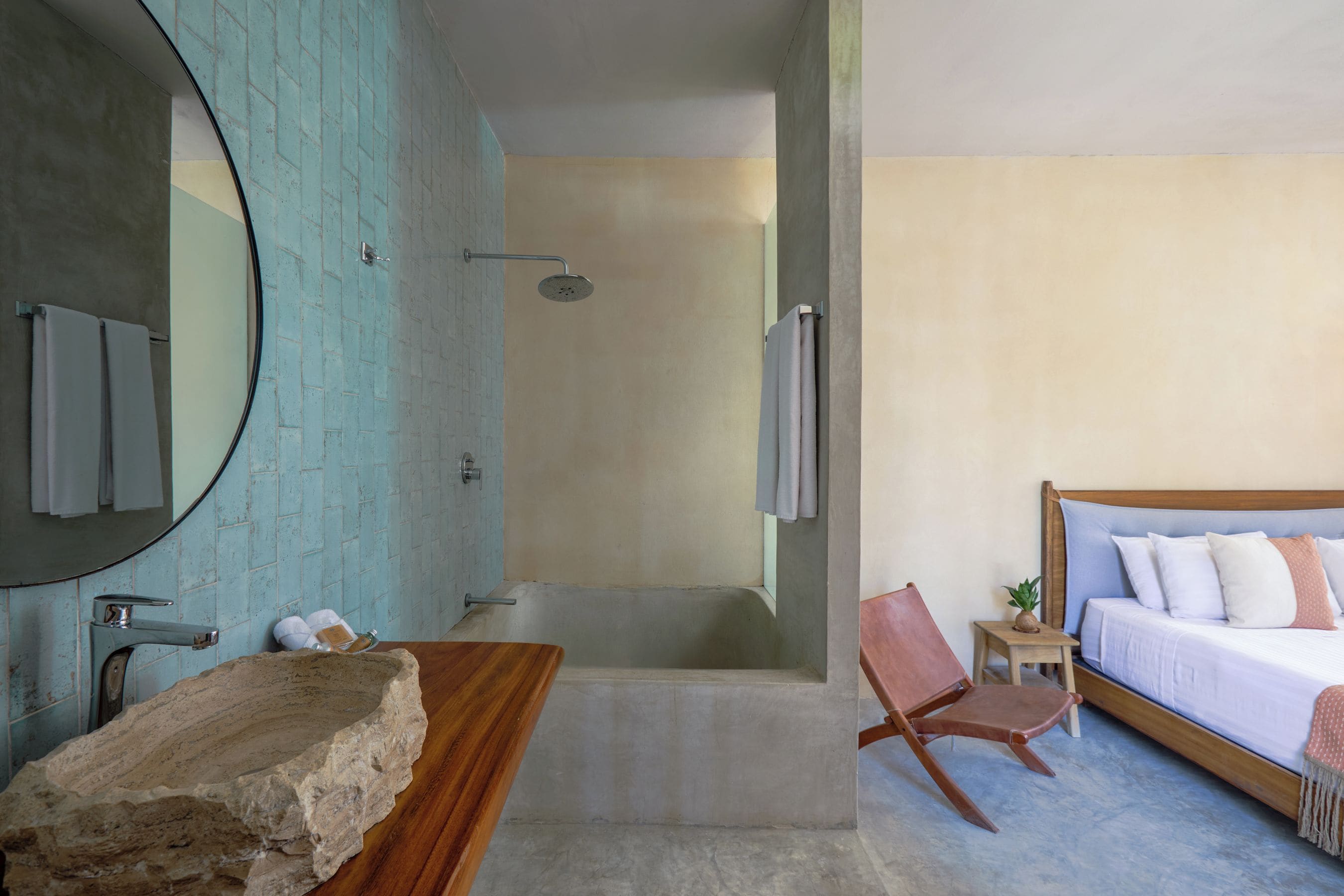 A bathroom with a bathtub, a shower, a wooden vanity with a stone basin, and a mirror.