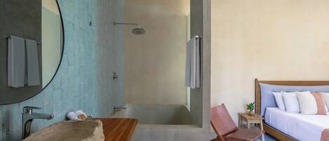 A bathroom with a bathtub, a shower, a wooden vanity with a stone basin, and a mirror.