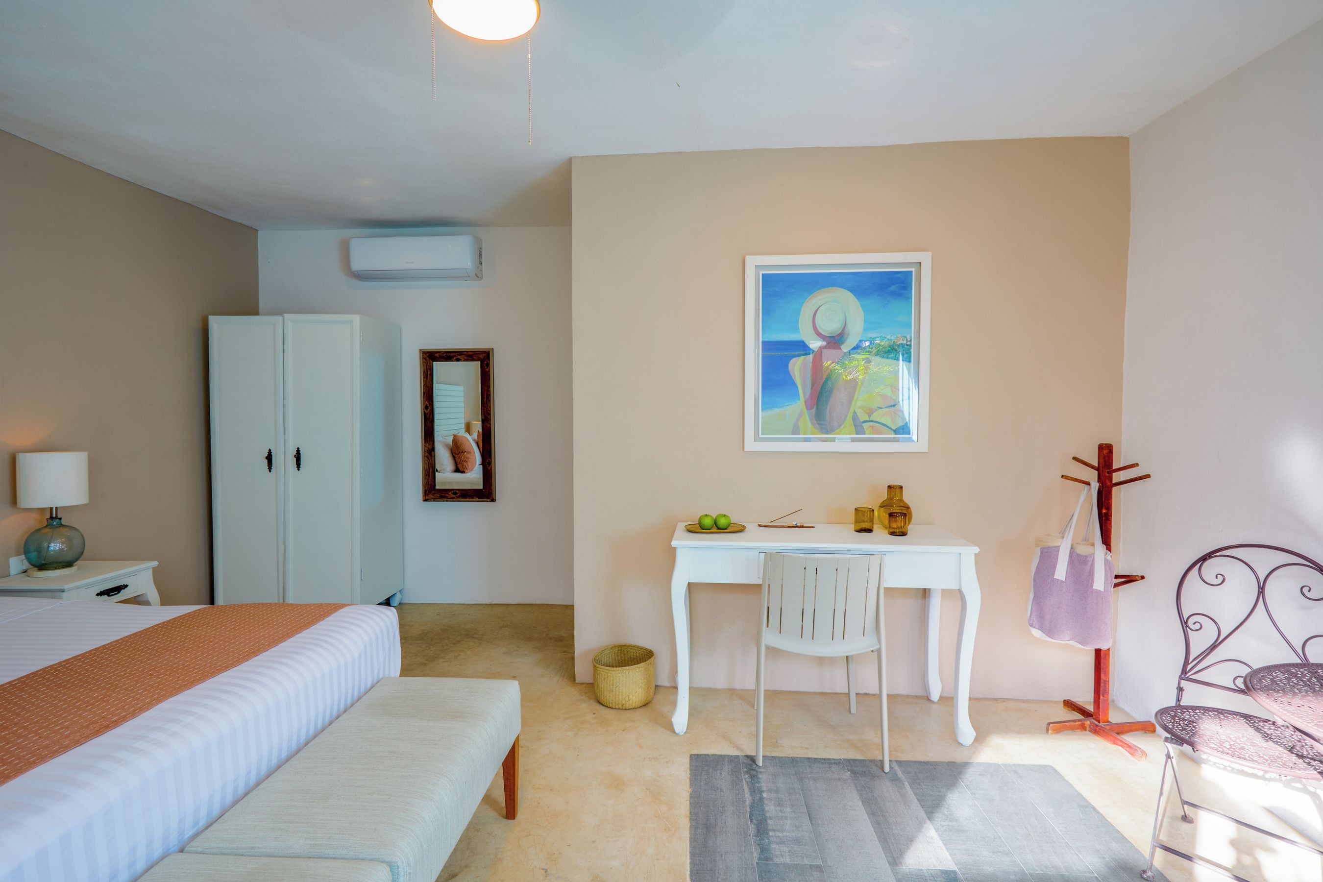Un dormitorio con cama, escritorio, silla, armario y un cuadro en la pared.