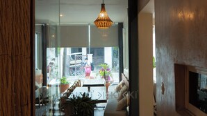 A modern interior with a large potted plant, a sofa, and a hanging light fixture. - Hotel Siesta Holbox (Isla Holbox)
