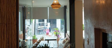A modern interior with a large potted plant, a sofa, and a hanging light fixture.