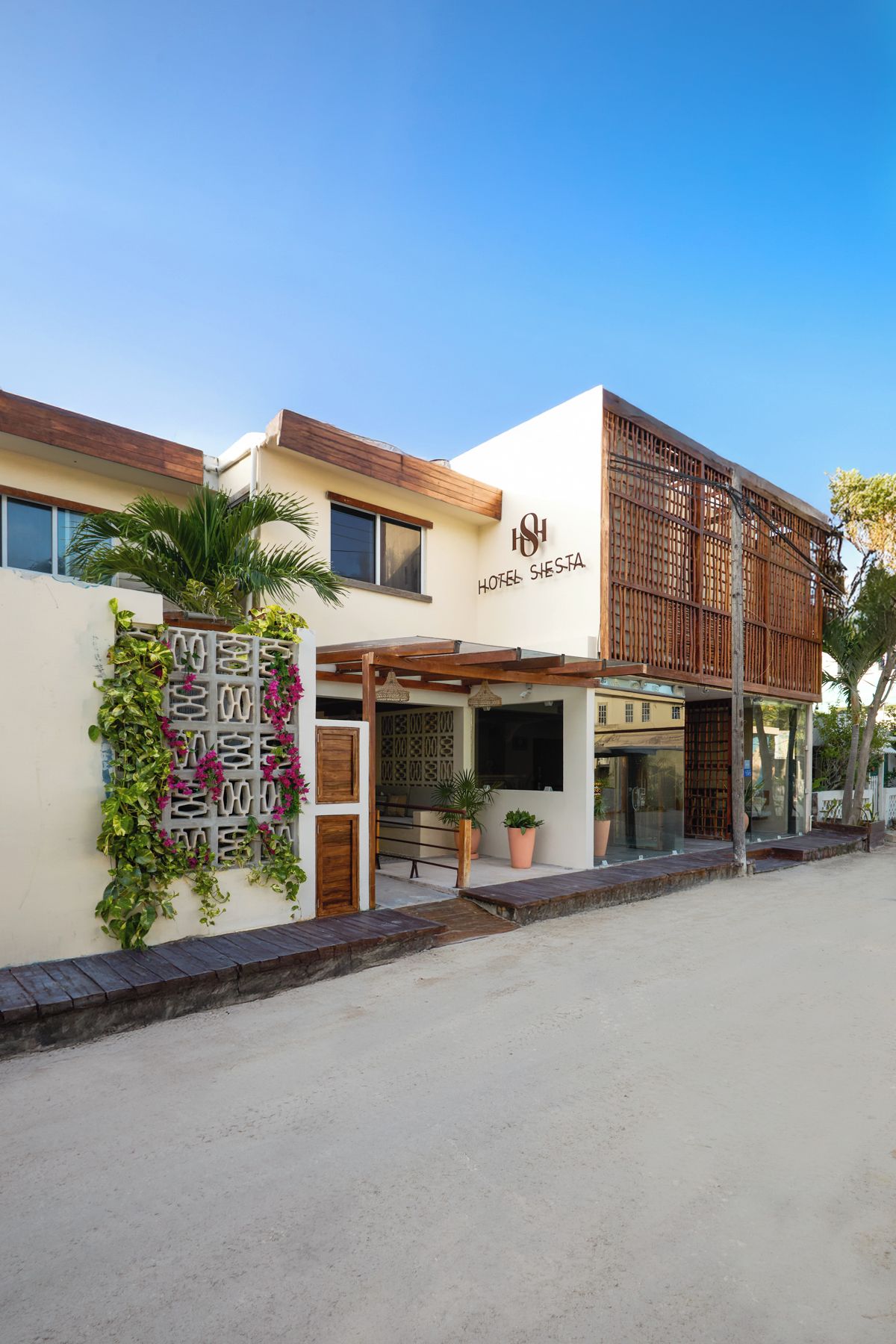 A hotel with a modern facade, a covered entrance, and a sign reading 'HOTEL SIESTA'.