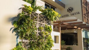 A building with a sign reading "HOTEL SIERRA" and a covered entrance area with plants. - Hotel Siesta Holbox (Isla Holbox)