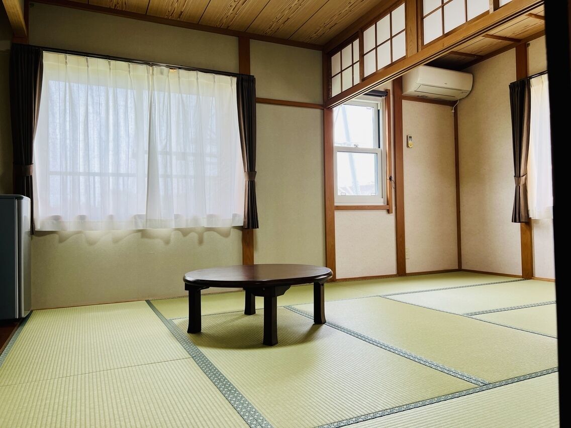 A traditional Japanese room with tatami flooring, a low table, and sliding doors.
