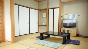 A traditional Japanese room with tatami flooring, a low table, cushions, sliding doors, and a television. - Pension AJIWAI (Nasu)