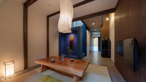 A modern interior with a wooden dining table, a hanging light fixture, and a television mounted on the wall. - Toji Akebono-an (Kyoto)