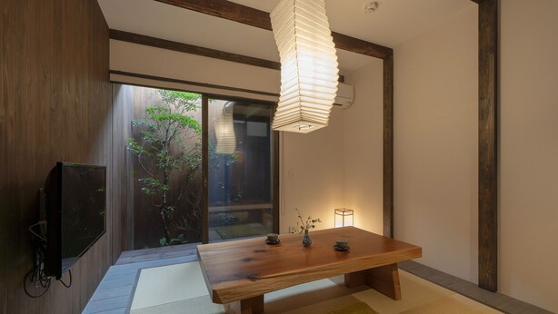 A traditional Japanese-style room with tatami flooring, a low wooden table, a television, and a hanging light fixture. - Toji Akebono-an (Kyoto)