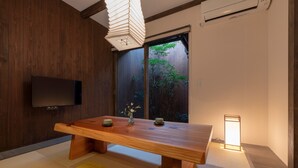 A traditional Japanese room with tatami flooring, a wooden table with two cups, a TV, and a sliding door leading to a garden. - Toji Akebono-an (Kyoto)