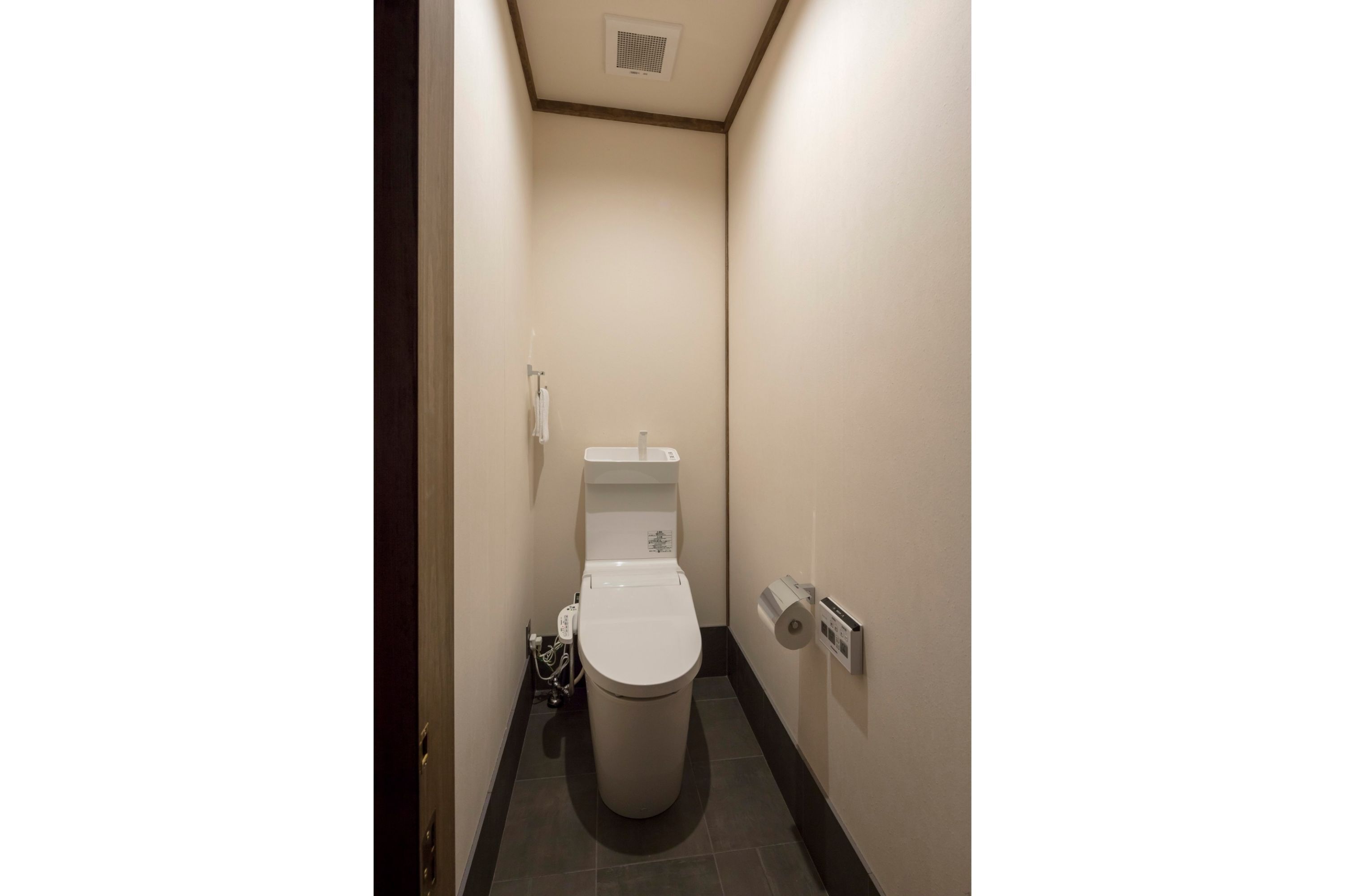 Une petite salle de bain étroite, équipée de toilettes, d’un lavabo et d’un porte-rouleau de papier toilette.