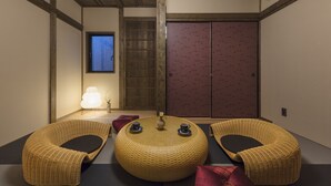 A traditional Japanese room with tatami flooring, a low wooden ceiling, and a sliding door. - Hanagoromo (Kyoto)