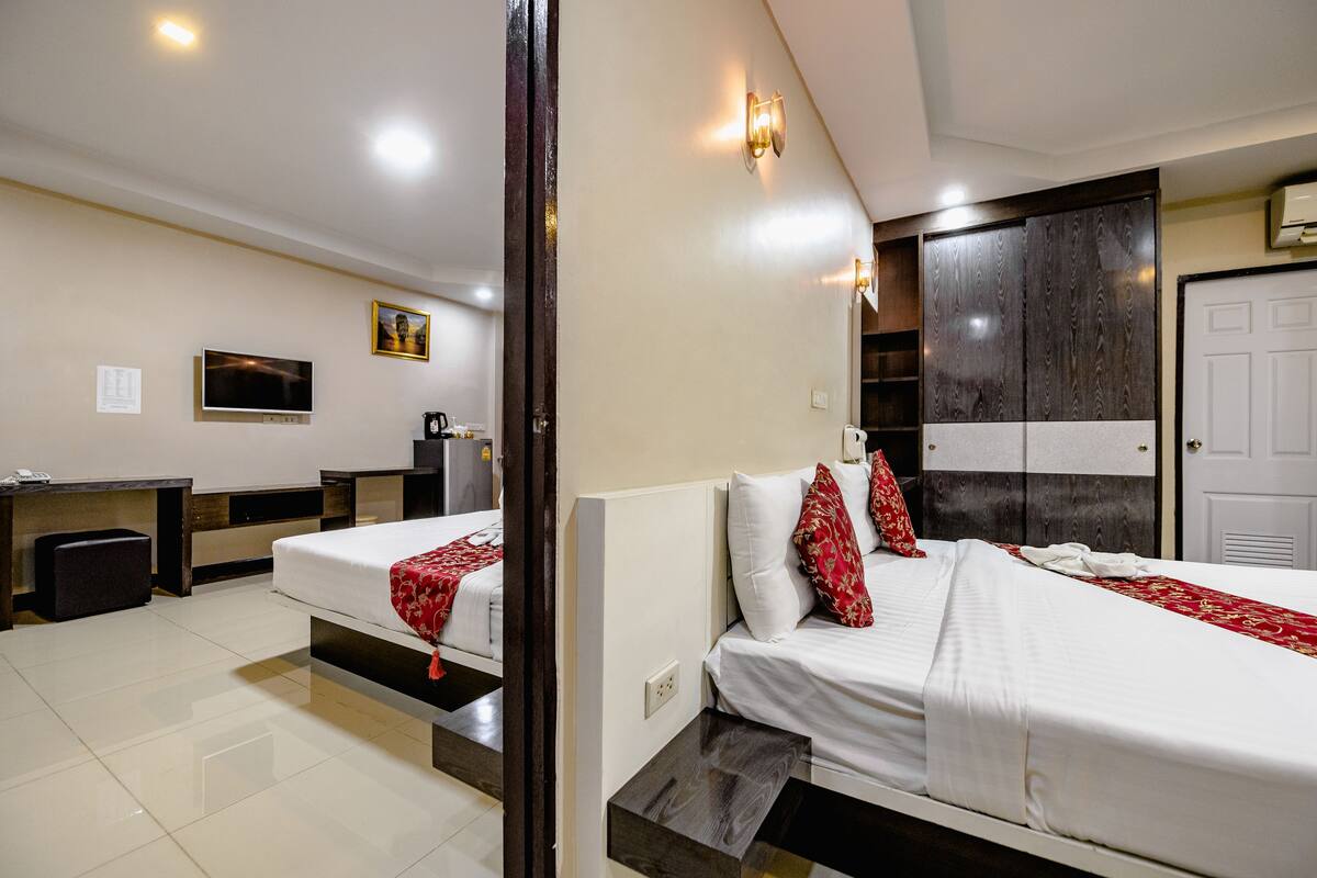 A hotel room with two beds, a desk, a television, and a wardrobe.