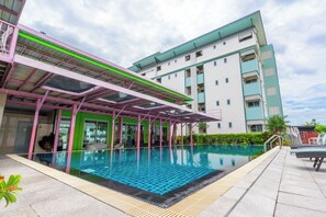 A swimming pool with a covered area, a multi-story building in the background, and a clear sky. - Gold Airport Suites (Bangkok)