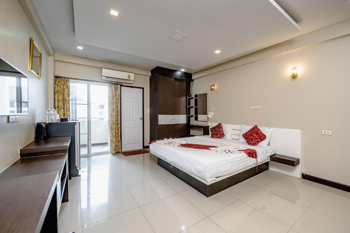A modern hotel room with a large bed, a desk, and a wardrobe.