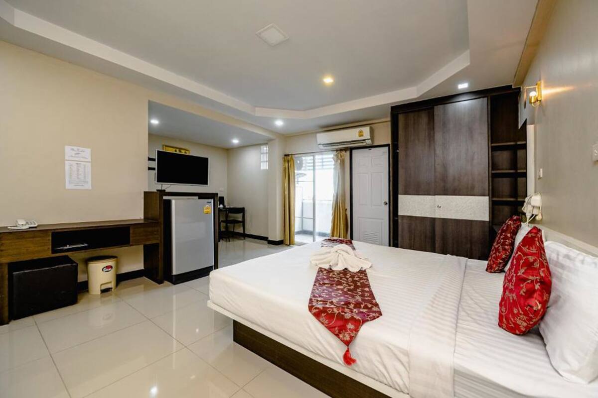 A hotel room with a bed, a desk, a television, and a wardrobe.