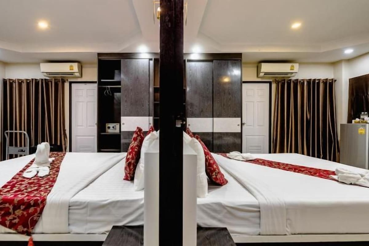 A mirrored room with two beds, a wardrobe, and a desk.