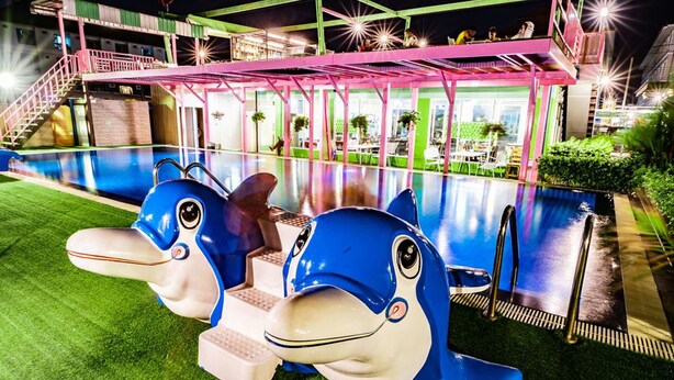 Zona de piscina con dos grandes estatuas de delfines azules y blancos.