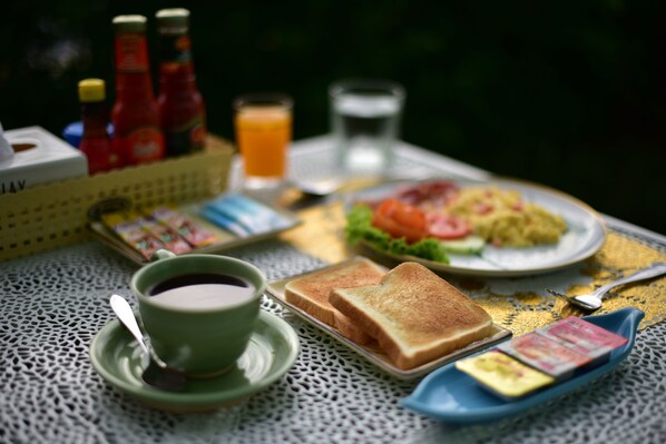 A table with a tray of toast, a cup of coffee, condiments, and a glass of orange juice. - Gold Airport Suites (Bangkok)
