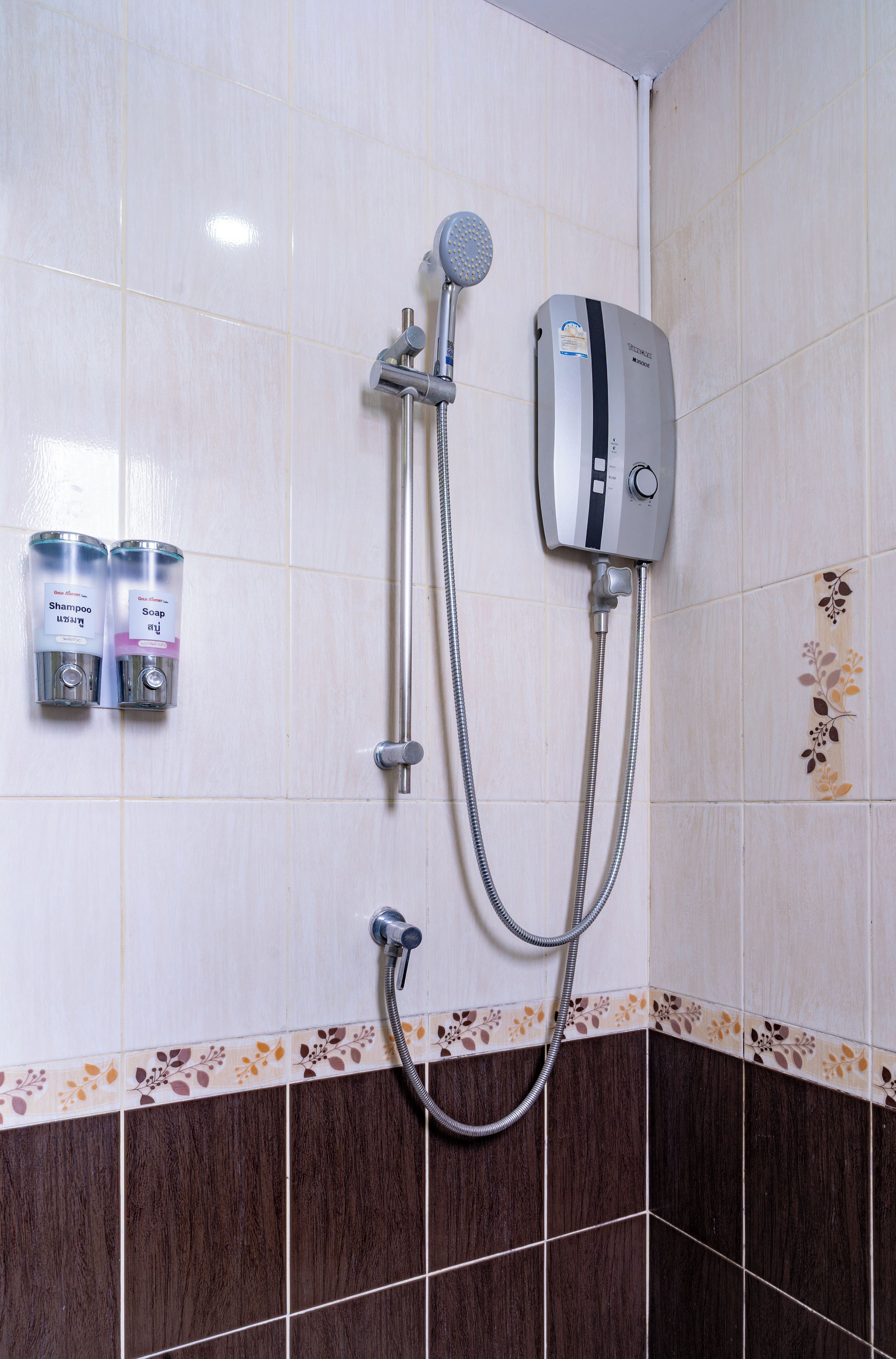 A bathroom with a shower, a handheld showerhead, a wall-mounted control unit, and two shampoo and soap dispensers.