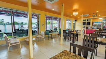 Un restaurante con mesas dentro, una zona de bar y vistas al exterior.