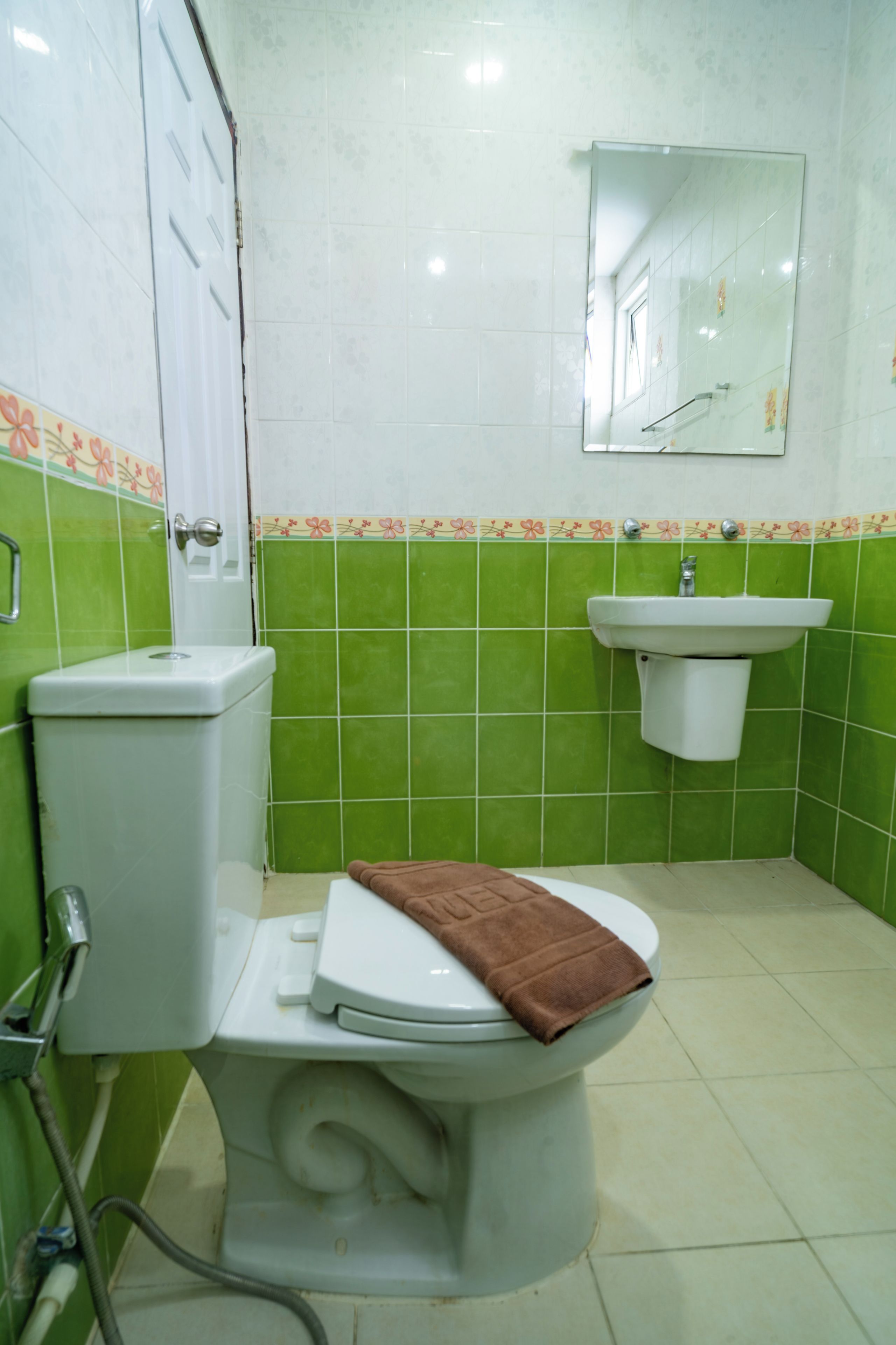 Een badkamer met toilet, wastafel en spiegel.