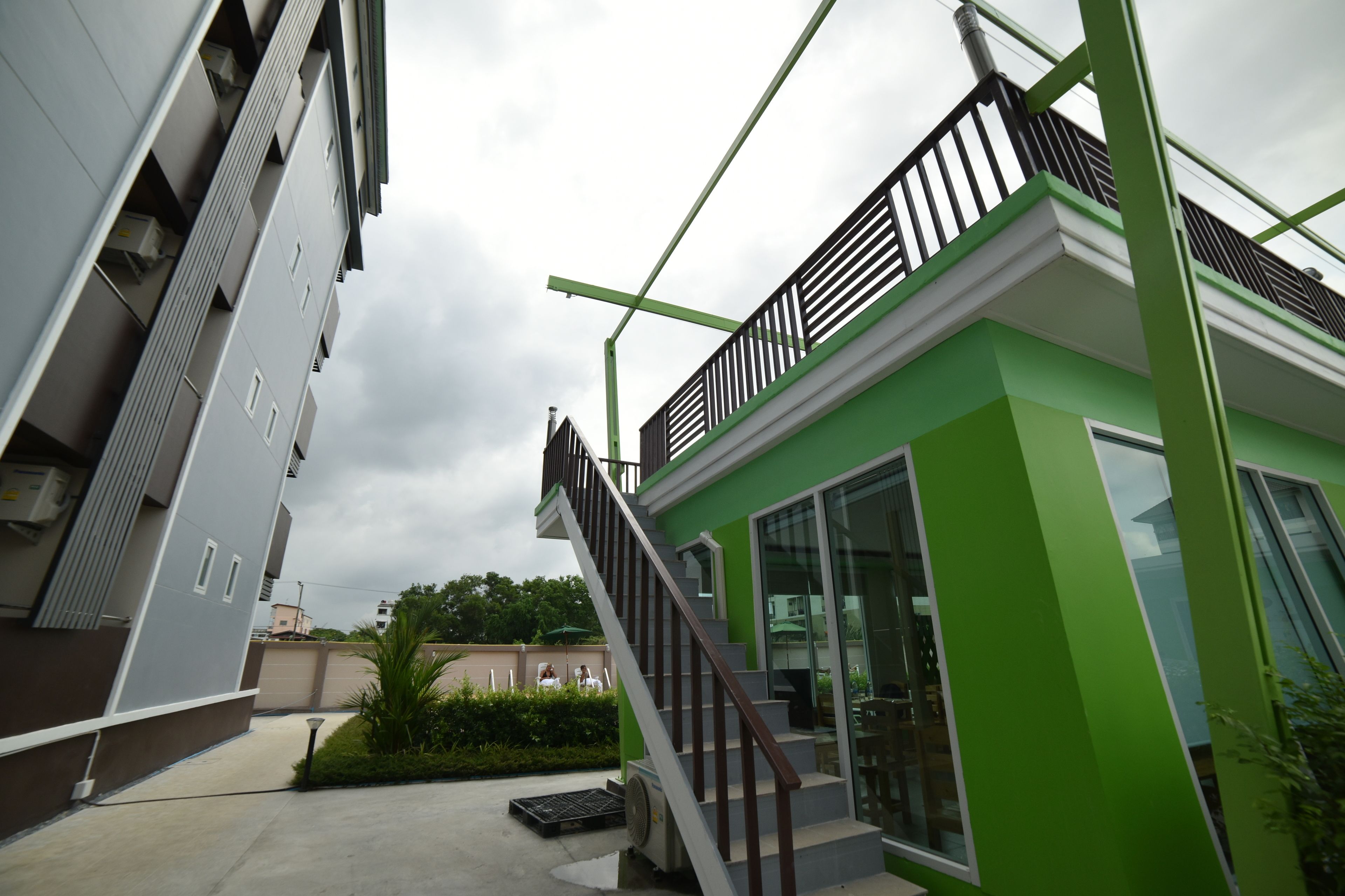 Un edificio moderno con fachada verde, una escalera y un balcón.