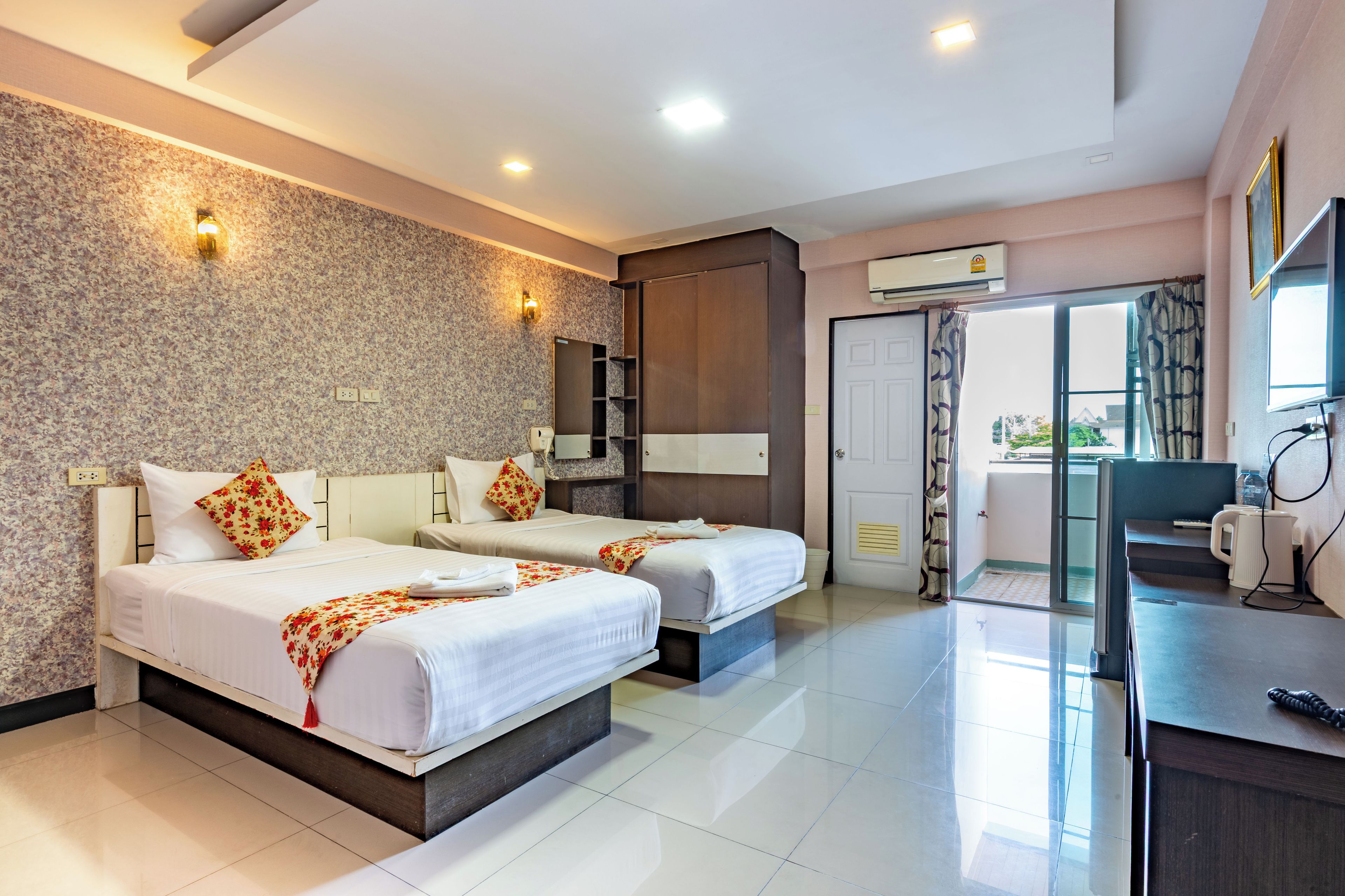 A hotel room with two beds, a desk, a mirror, and a bathroom door.