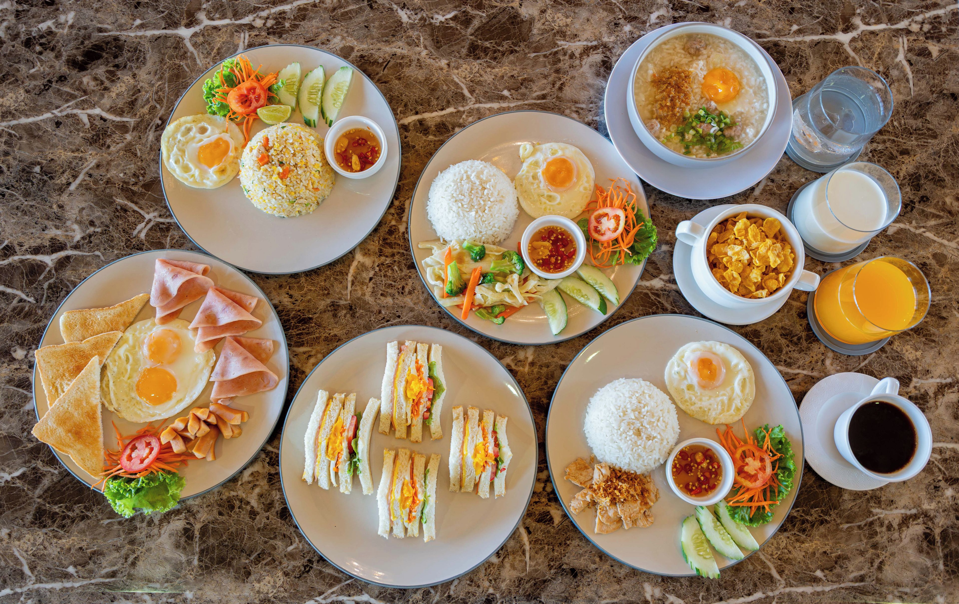 A variety of dishes including rice, eggs, and salads, arranged on plates on a marble table.
