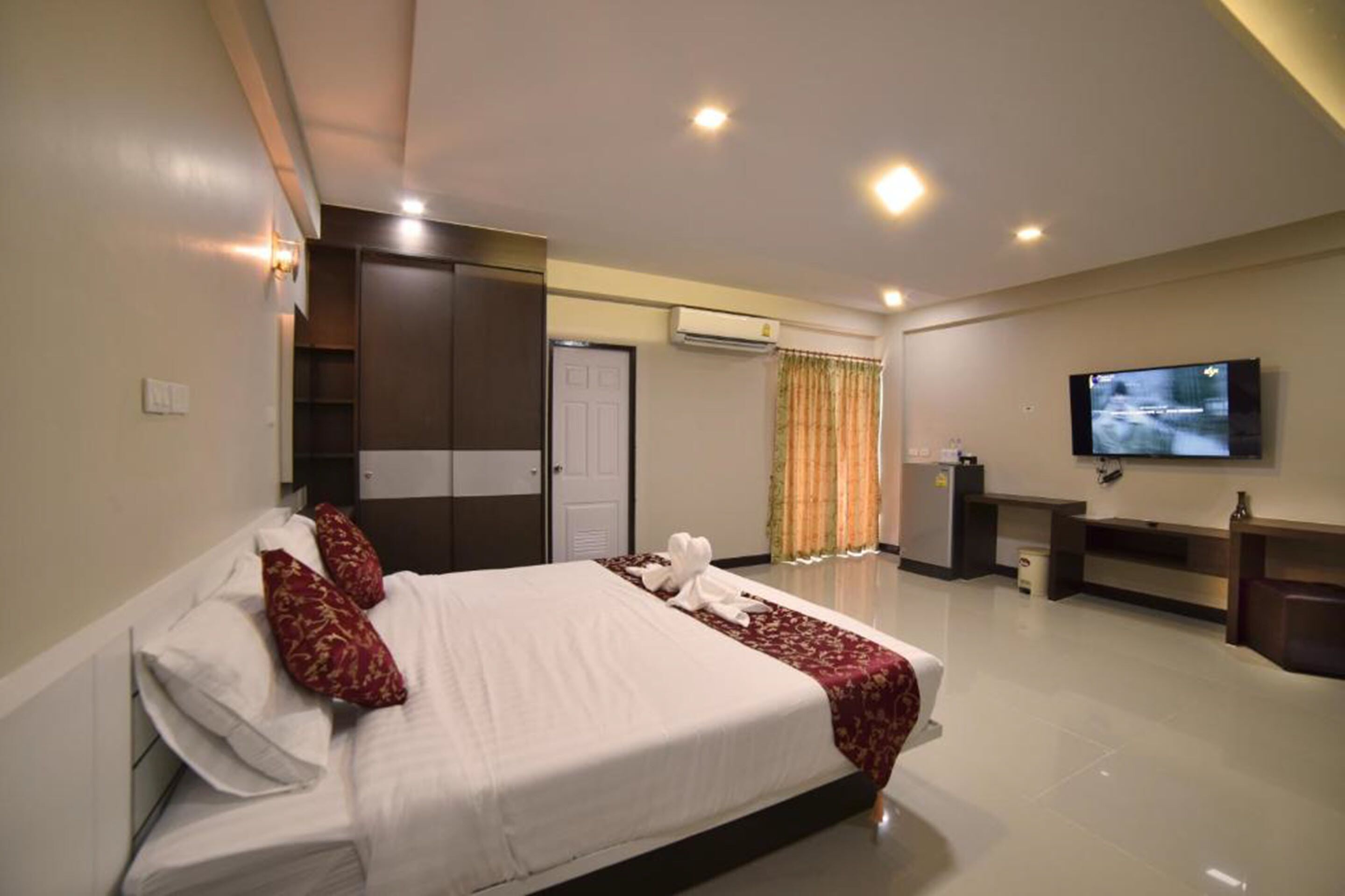 A hotel room with a large bed, a TV mounted on the wall, and a desk with a chair.