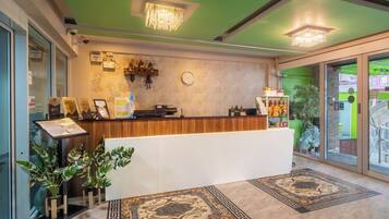 A reception area with a wooden counter, a clock, and a green wall.