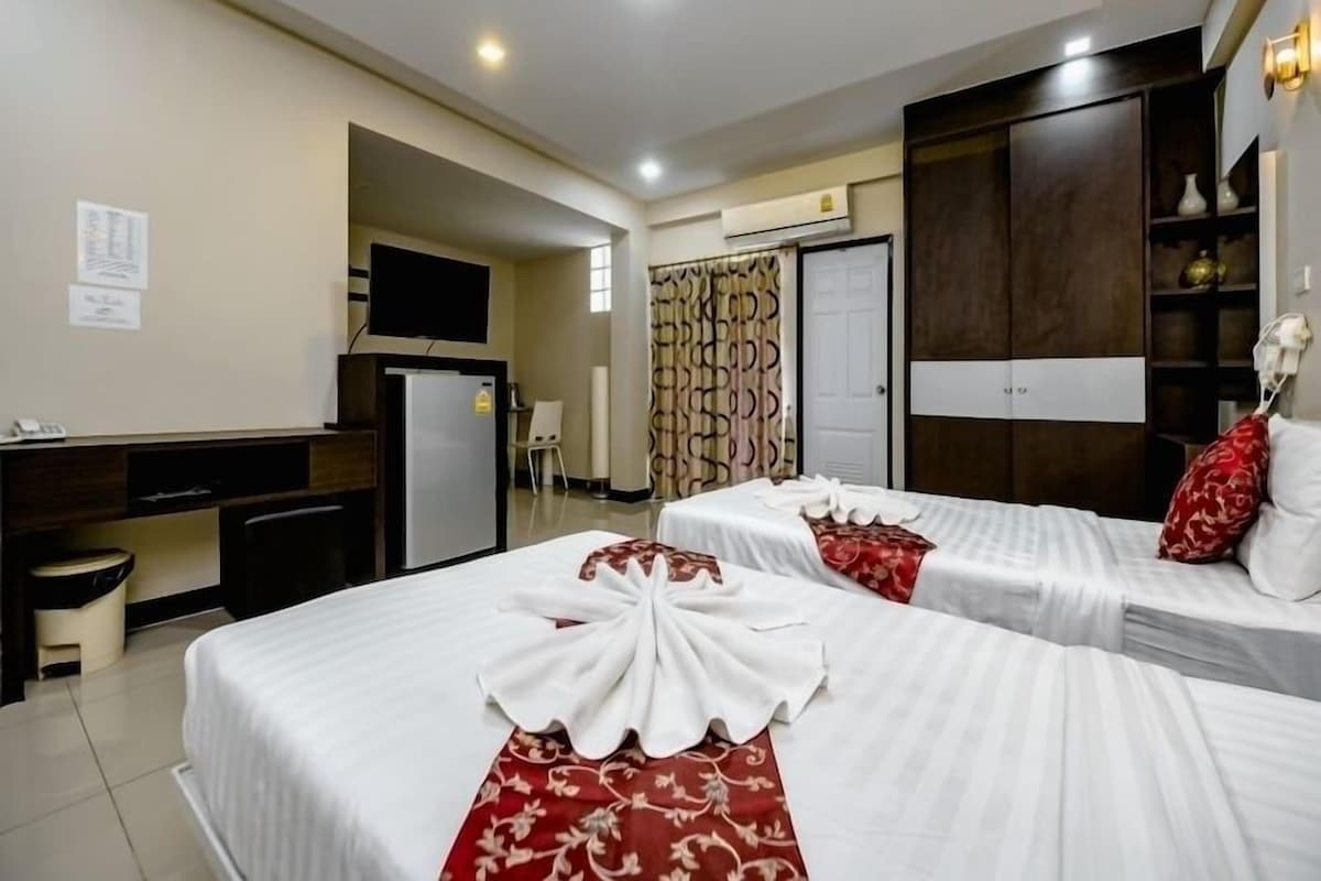 A hotel room with two beds, a desk, a chair, a TV, and a wardrobe.