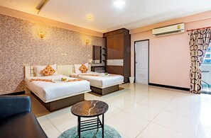 A hotel room with two beds, a small table, a chair, a bathroom, and an air conditioning unit. - Gold Airport Suites (Bangkok)