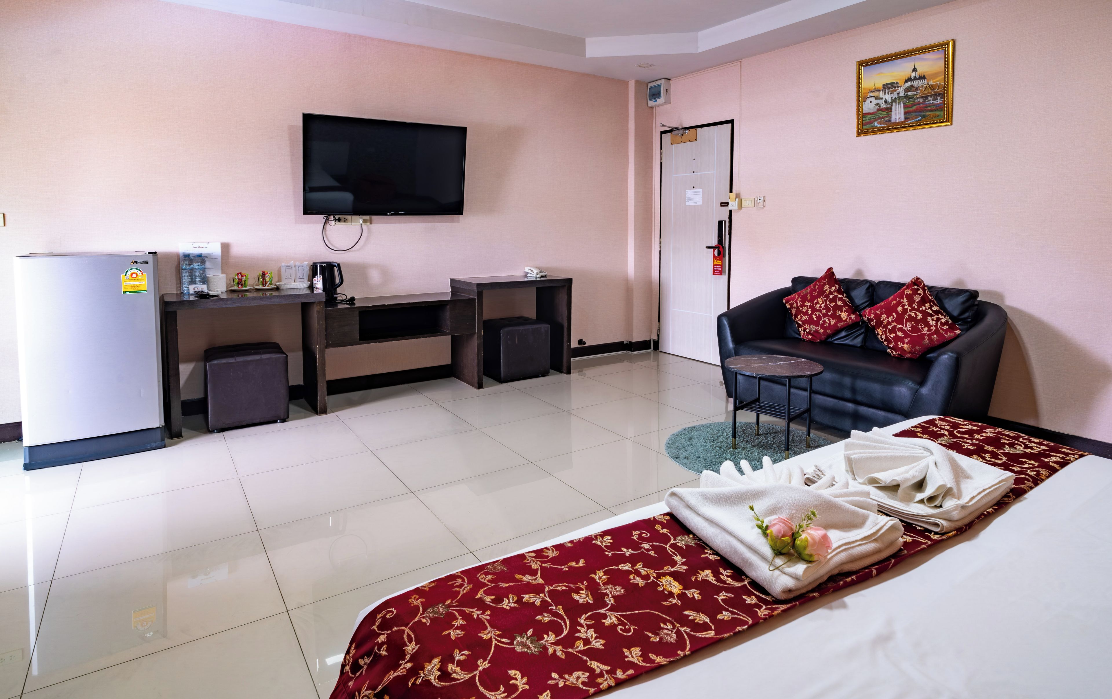 A hotel room with a bed, a TV, a desk, a couch, and a small table.