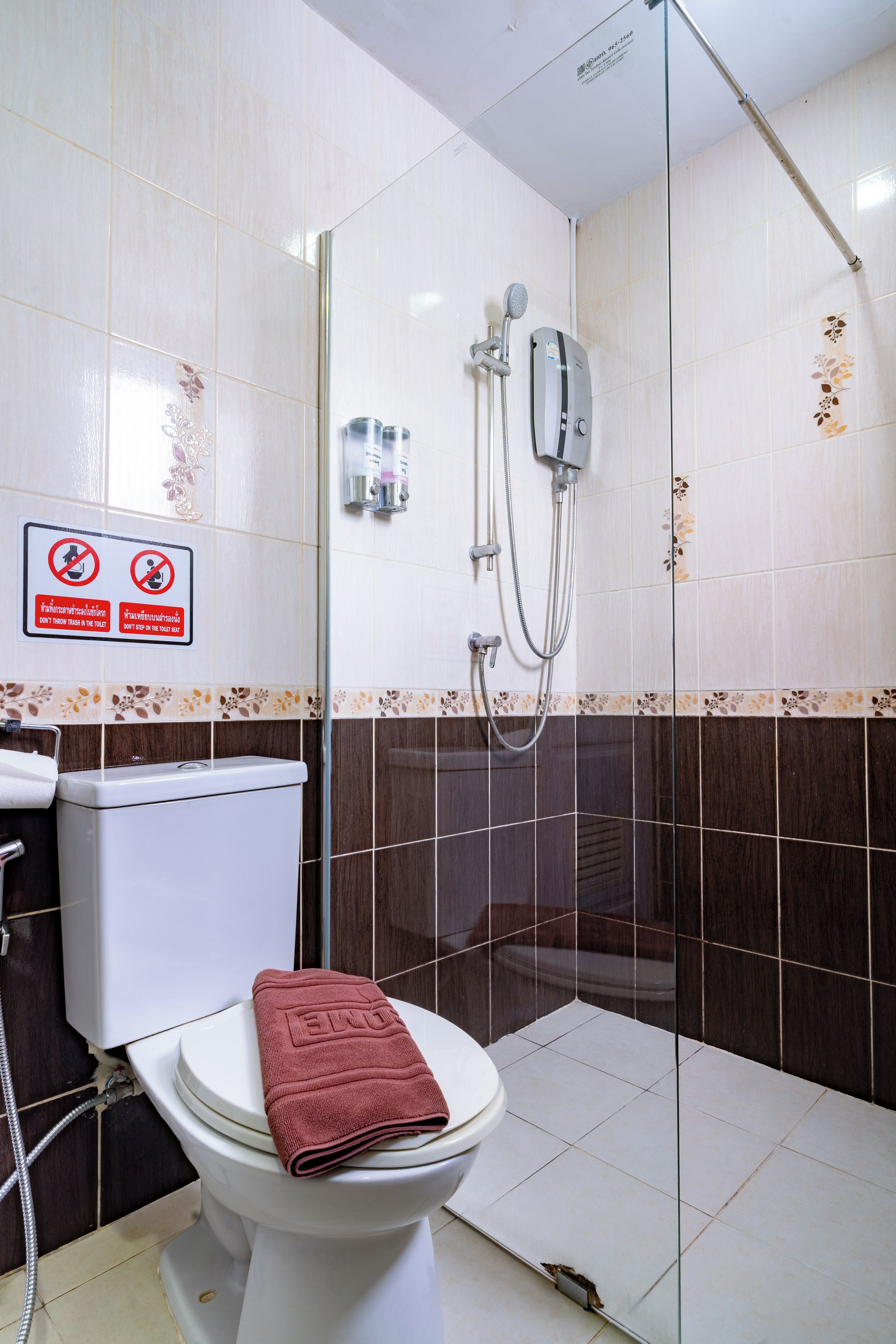 Un baño con inodoro, ducha y zona de ducha con mampara de vidrio.