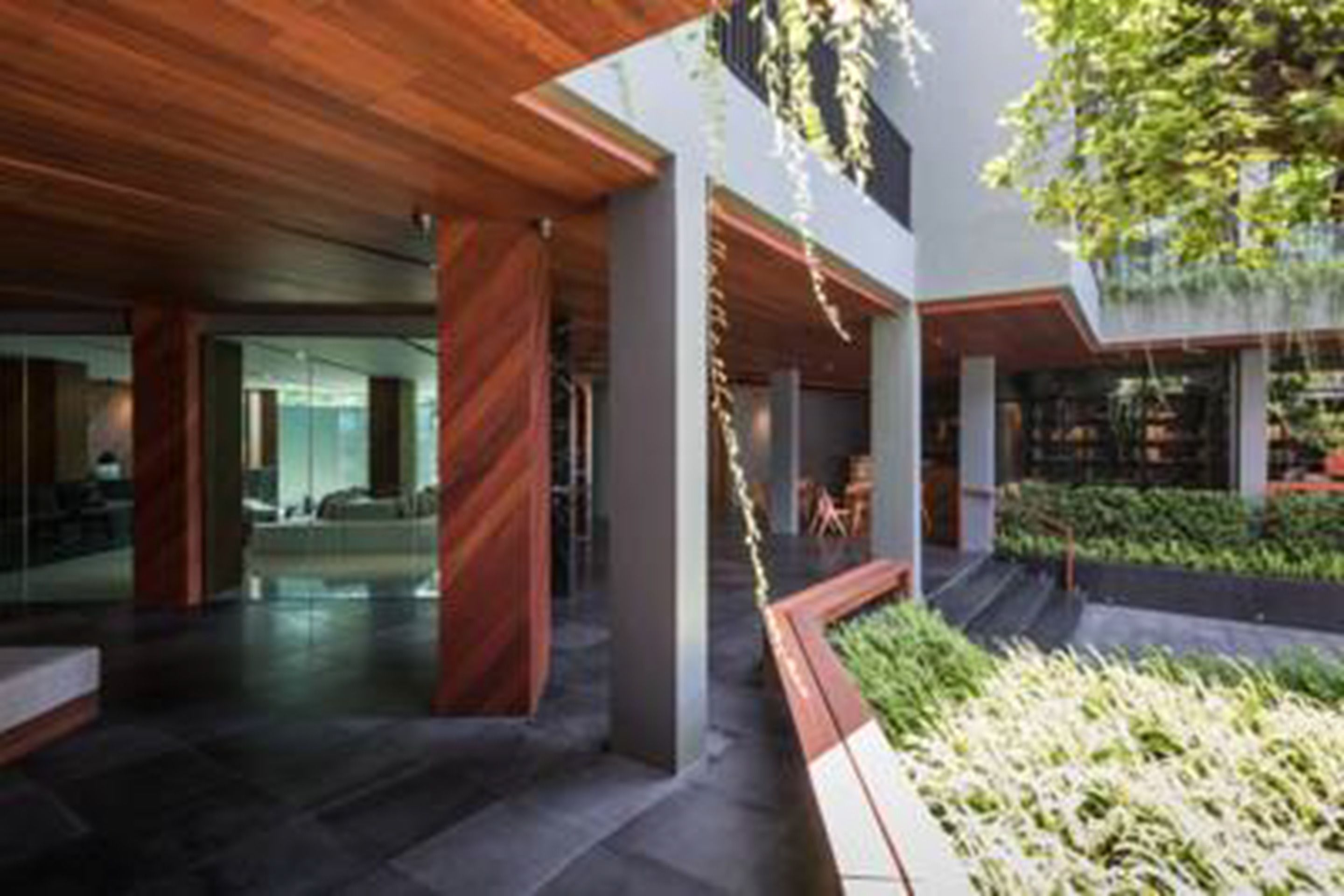 A modern interior with a wooden ceiling, a central garden area, and a seating space.