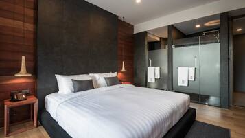 A modern bedroom with a large bed, dark walls, and a wooden floor.