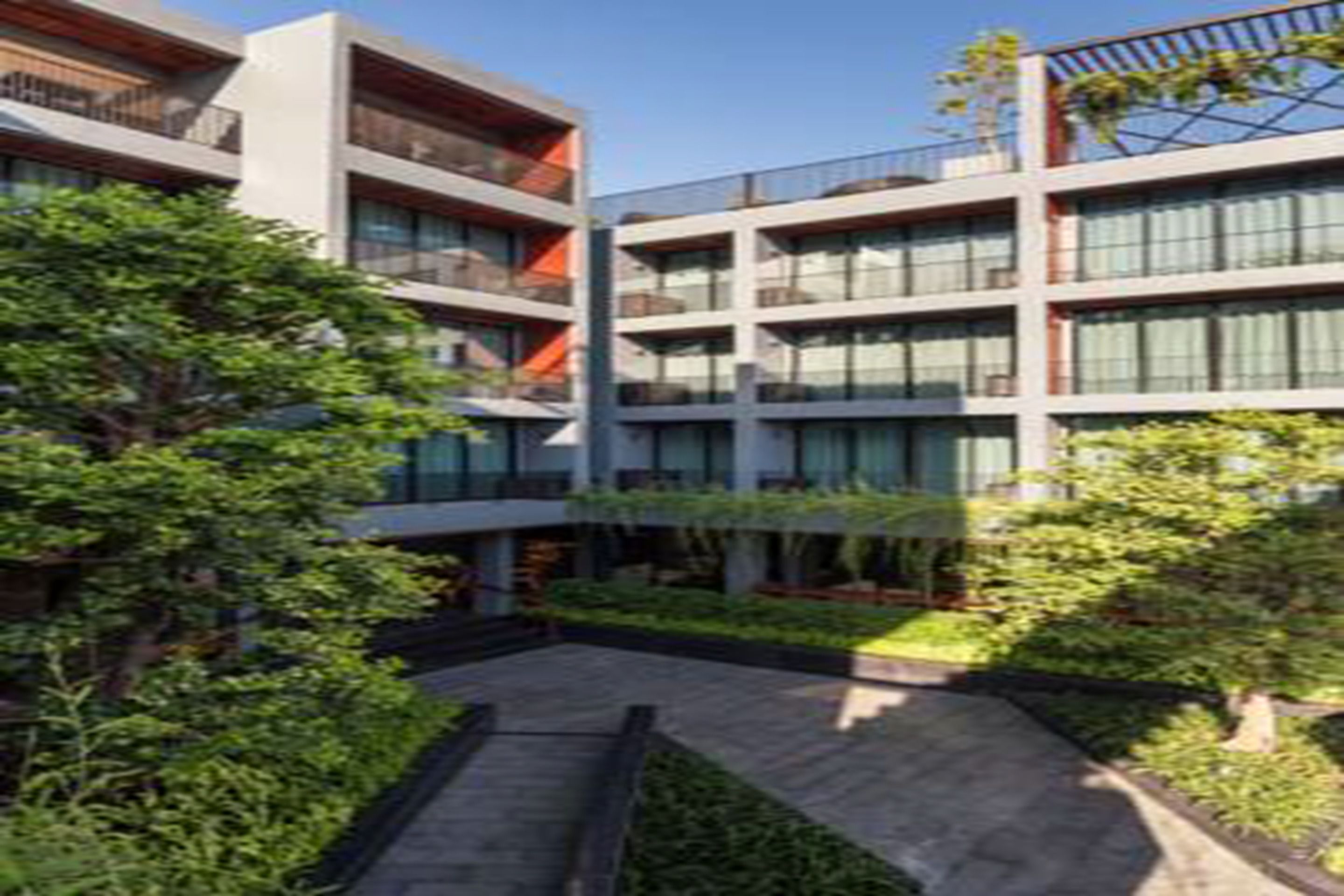 Un edificio moderno de varios pisos con balcones y grandes ventanales.
