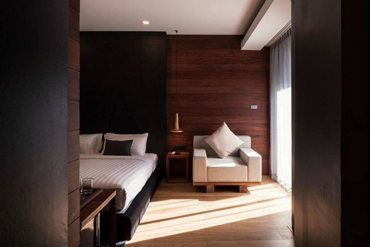 Een moderne slaapkamer met een bed, nachtkastje, bank en lamp.