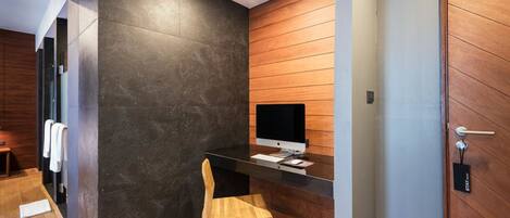Una moderna recepción con un monitor de computadora, una silla de madera y una pared oscura con textura.