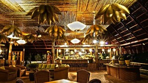 Uma área de bar interna com móveis de vime, luminárias pendentes e balcão.